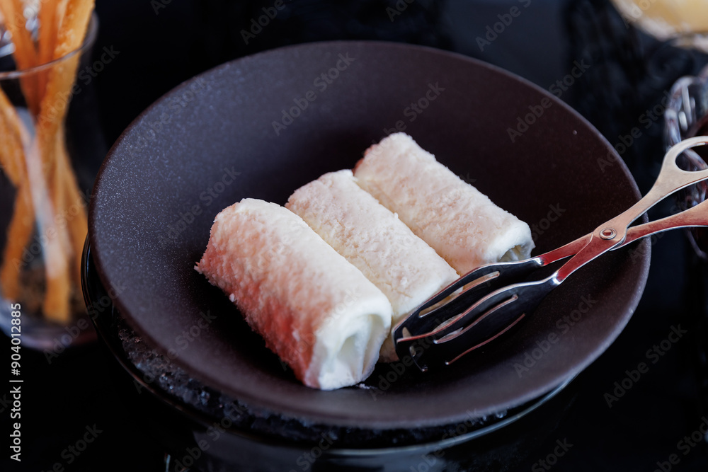 Delicious Turkish Kaymak Rolls in a Black Bowl with Serving Tongs