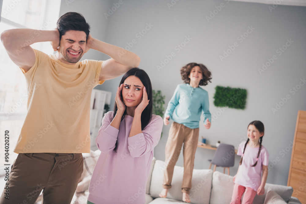 Photo of annoyed angry parents dressed casual clothes suffering children noise indoors house apartment room Photo of annoyed angry parents dressed casual clothes suffering children noise indoors house apartment room