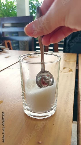 Vertical pov of scooping refine sugar from a glass container