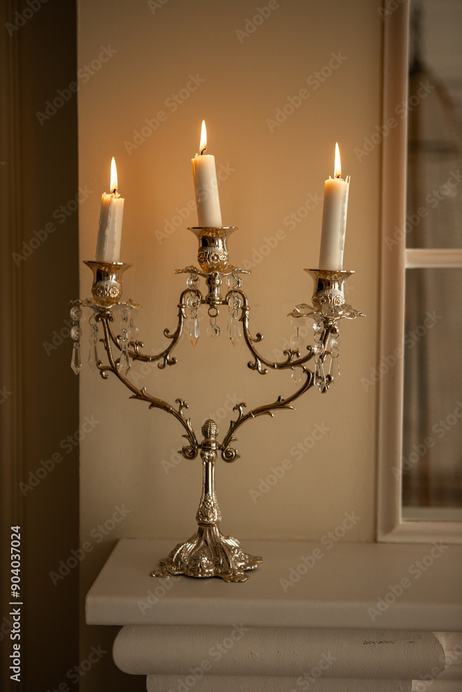 a silver candelabra with a white candles on top of it in a room a silver candelabra with a white candles on top of it in a room