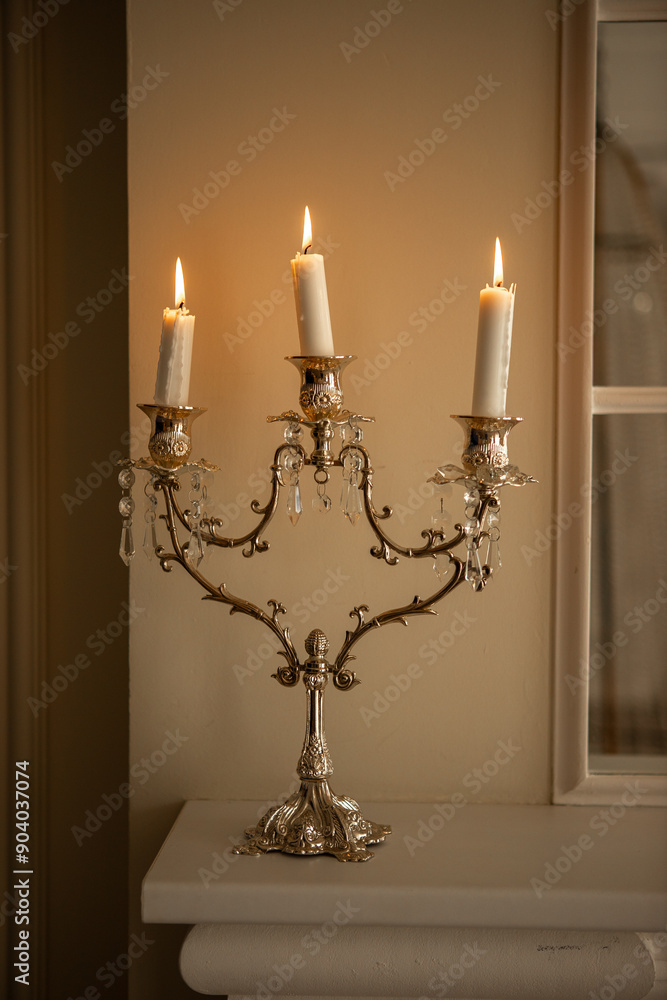 a silver candelabra with a white candles on top of it in a room a silver candelabra with a white candles on top of it in a room