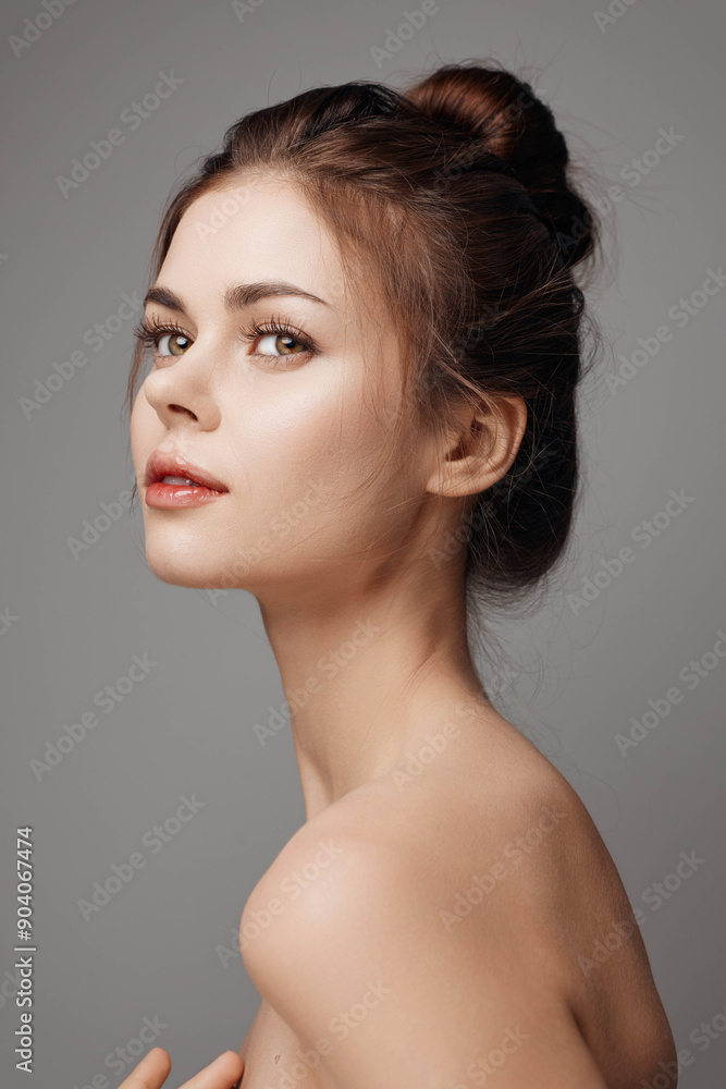 Beautiful young woman with hands on head posing on gray background Beautiful young woman with hands on head posing on gray background