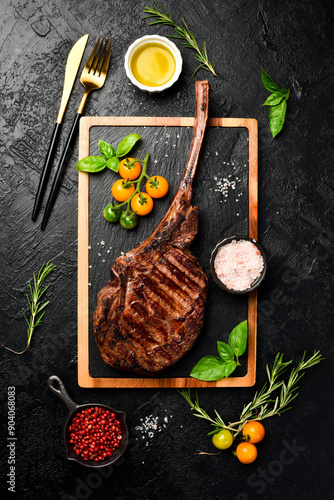 Grilled Tomahawk steak on the bone with salt, butter and pepper. Prime Black Angus beef steak on a black slate background. Top view. photo