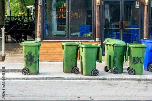 Photography green composte recycling bins on the sidewalk outside a restaurant having been e