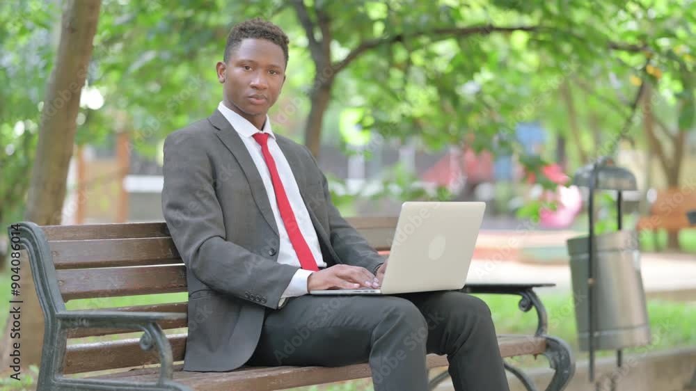 African Businessman Looking at Camera with Laptop in Lap Outdoor African Businessman Looking at Camera with Laptop in Lap Outdoor