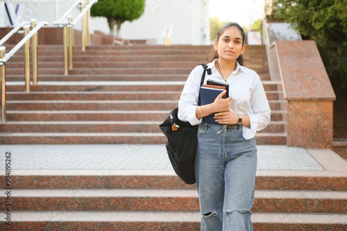 Portrait of a cheerful smart student girl studying with books. Indian student educational young teenager girl at outside campus