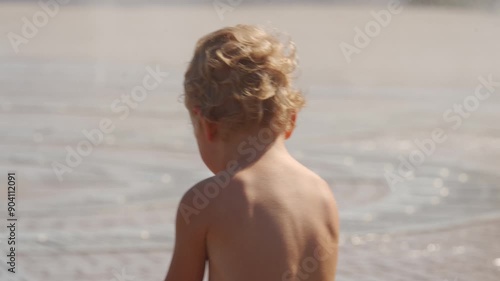 Happy wet child run barefoot bathing in fountain water streams in summer. Light and music fountain on the Tereshkova embankment. Yevpatoria, Crimea, Russia 2024 photo