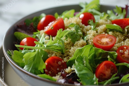 Fresh quinoa salad with tomatoes and arugula in bowl.