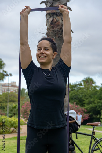 Young woman smiling exercising with resistance band in park