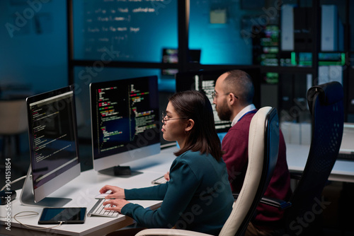 High angle view at two people sitting at workplace in cybersecurity department and writing code in blue lights © Mediaphotos
