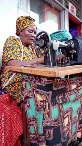 African woman in outdoor workshop using ancient sewing machine