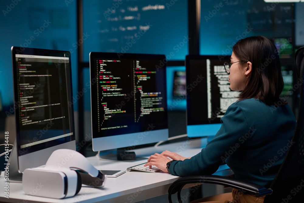 Female IT developer writing code for VR project at office workplace with focus on computer screens copy space Female IT developer writing code for VR project at office workplace with focus on computer screens copy space