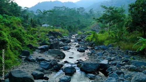 Drone shot of natural forest river with panoramic of green mountain