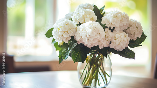 bouquet of white hydrangeas in an elegant glass vase, placed on the dining table with a blurred living room background