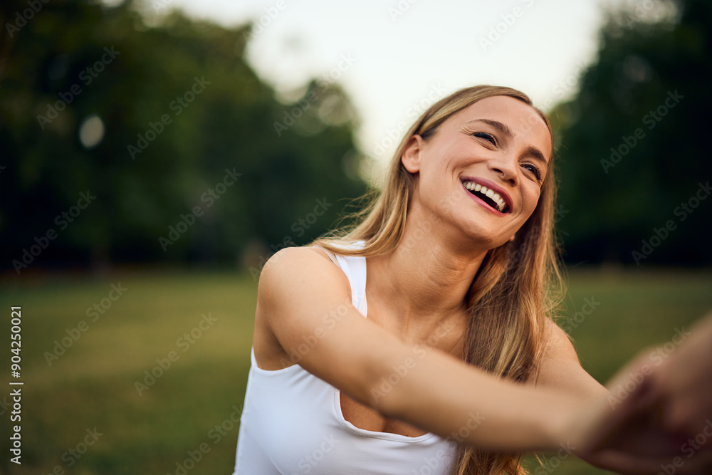 A happy blonde girl sitting in the park, laughing with her partner. A happy blonde girl sitting in the park, laughing with her partner.