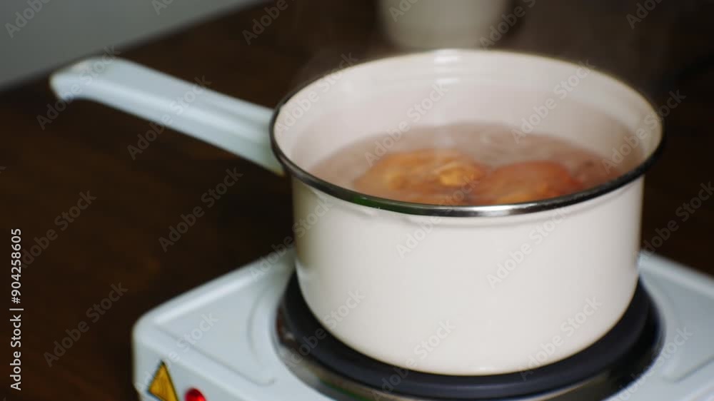 Preparing Breakfast with organic eggs and minimum of food. High-protein diet. Side Cinematic Close-up view. Eggs are cooked in small enamelled ladle on miniature electric stove Preparing Breakfast with organic eggs and minimum of food. High-protein diet. Side Cinematic Close-up view. Eggs are cooked in small enamelled ladle on miniature electric stove