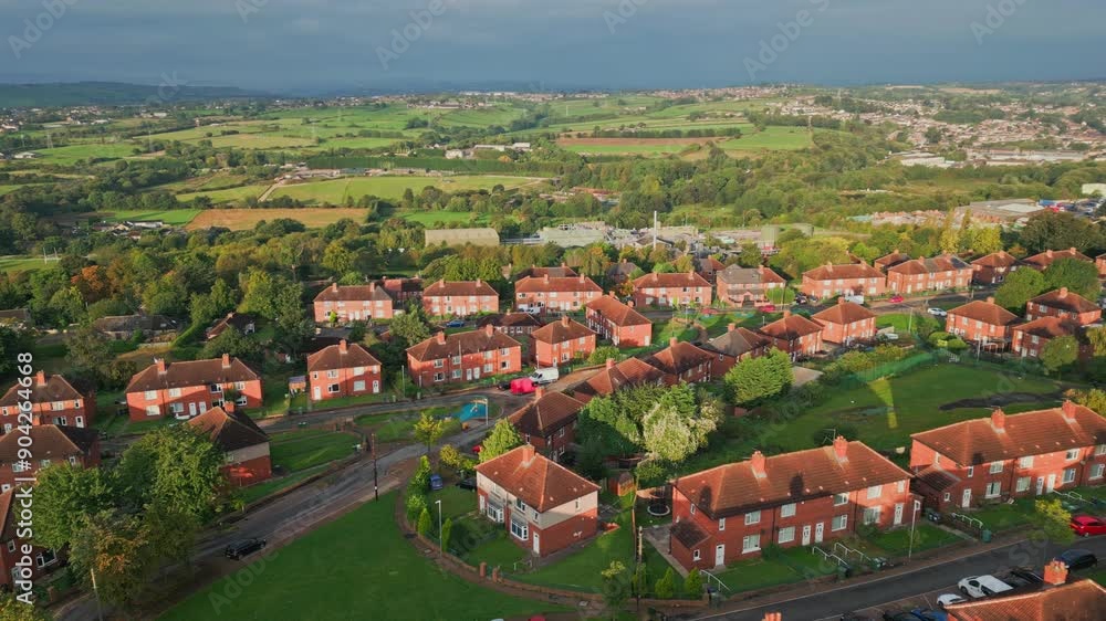 UK housing district: Aerial view of Yorkshire's red brick council estate, lit by the morning sun, featuring homes and people on the streets. UK housing district: Aerial view of Yorkshire's red brick council estate, lit by the morning sun, featuring homes and people on the streets.