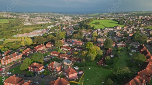 UK city housing: Aerial view of Yorkshire's red brick council estate, bathed in morning sunlight, with a vibrant atmosphere and residents.