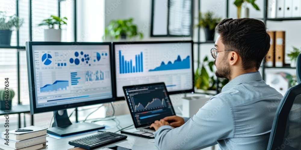 A professional in a modern office space, typing on a laptop, with multiple monitors displaying graphs and data analysis A professional in a modern office space, typing on a laptop, with multiple monitors displaying graphs and data analysis
