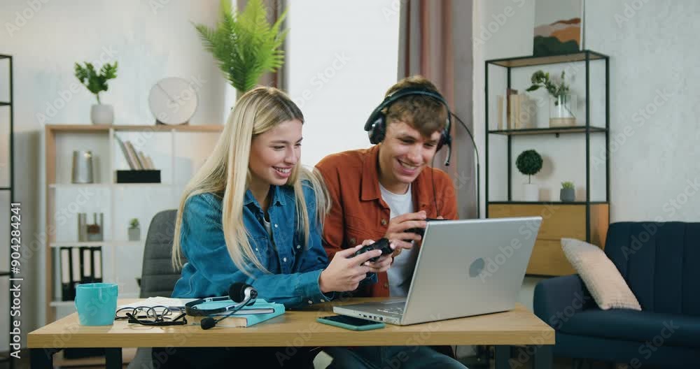 Young man and woman couple enjoying videogames on laptop at home and feeling happiness because winning and raising their hands. Leisure concept Young man and woman couple enjoying videogames on laptop at home and feeling happiness because winning and raising their hands. Leisure concept