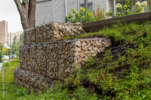 Gabion fence and black geogrid. Strengthening the slope. Reinforcement with gravel and metal mesh photo