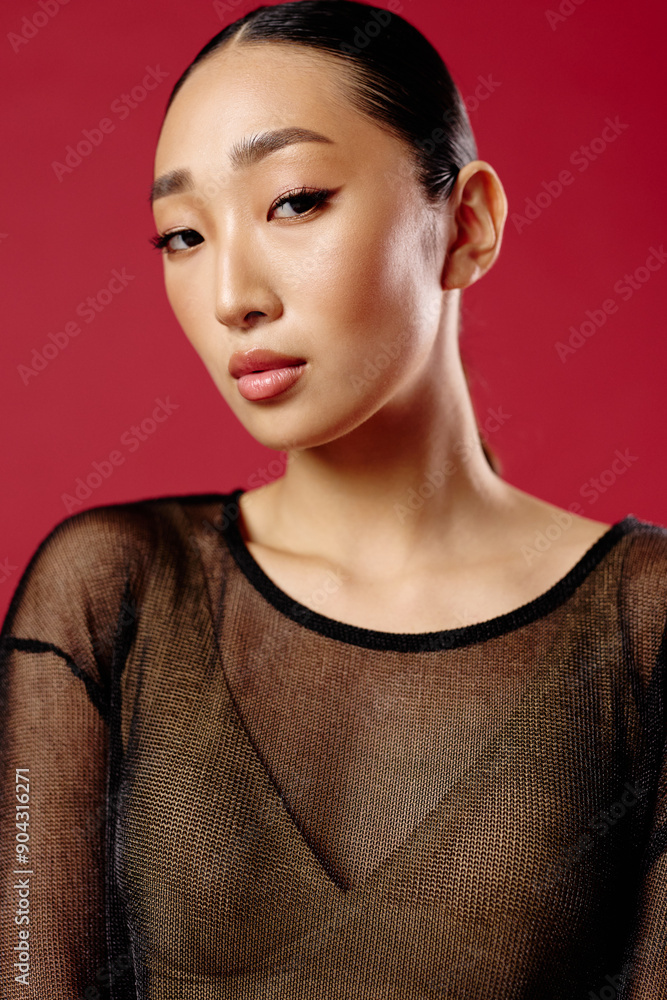 Fashion, asian woman in sheer top posing against red background with eyes closed and hair in ponytail Fashion, asian woman in sheer top posing against red background with eyes closed and hair in ponytail