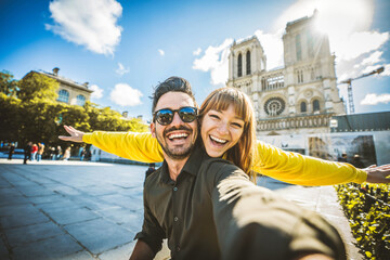 Happy couple of tourists visiting Notre Dame Cathedral in Paris, France - Boyfriend and girlfriend enjoying romantic vacation in Europe - Holidays and travel concept