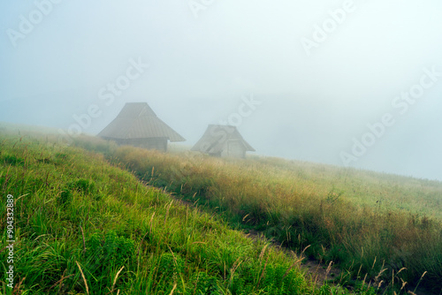 Shepard's cabins in Bieszczady mountain range during cloudy day and rainy weather photo