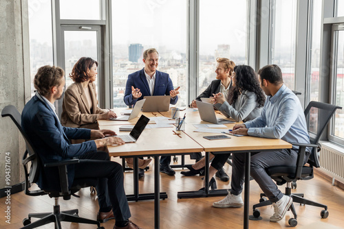 Fotografie A group of five professionals are seated around a large, rectangular table in a modern office