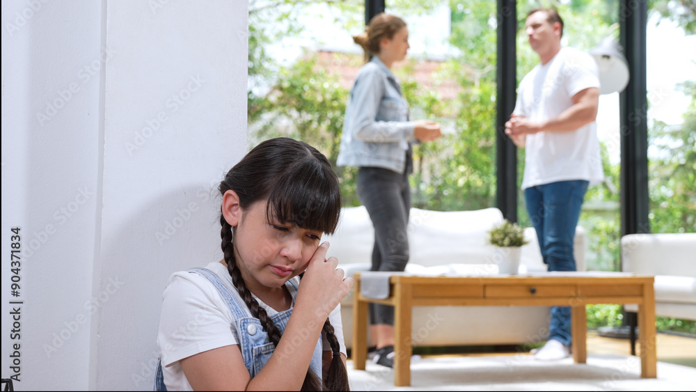 Stressed and unhappy young girl huddle in corner, cover her ears blocking sound of her parent arguing in background. Domestic violence at home and traumatic childhood develop to depression. Synchronos Stressed and unhappy young girl huddle in corner, cover her ears blocking sound of her parent arguing in background. Domestic violence at home and traumatic childhood develop to depression. Synchronos
