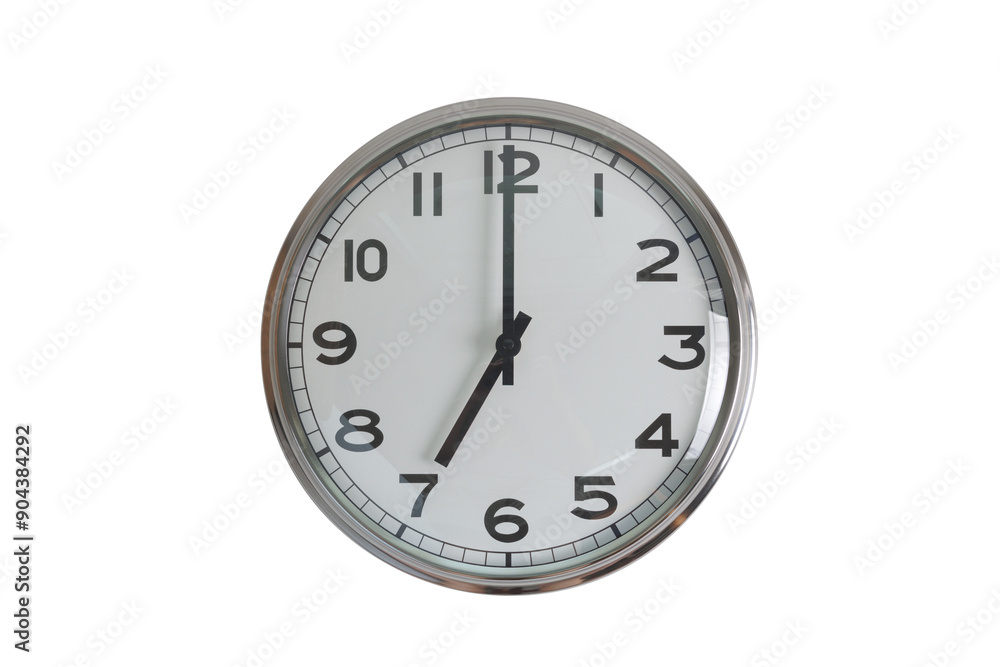 A white round shape wall clock with black hands showing the time of 7 o'clock cutout from background. Short hand at 7 o'clock and long hand at number 12. A white round shape wall clock with black hands showing the time of 7 o'clock cutout from background. Short hand at 7 o'clock and long hand at number 12.