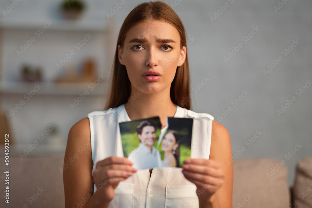Divorce. Upset Woman Tearing Apart Wedding Photo With Ex-Husband After Breakup Sitting On Sofa Indoor. Selective Focus Divorce. Upset Woman Tearing Apart Wedding Photo With Ex-Husband After Breakup Sitting On Sofa Indoor. Selective Focus