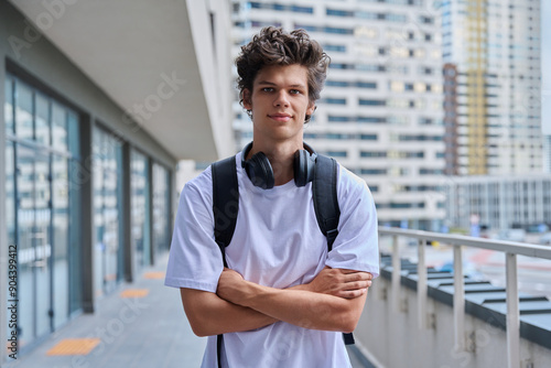 Handsome young man looking at camera outdoors, modern skyscrapers urban style background photo