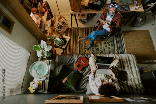 Top view shot of two roomies having break during remote work day, they talking to each other and chilling photo