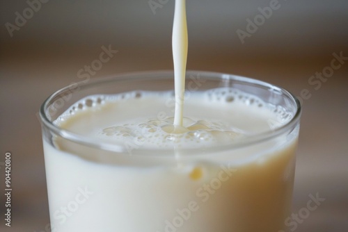 A close-up shot of fresh milk being poured into a glass, capturing the smooth texture and bubbles forming on the surface