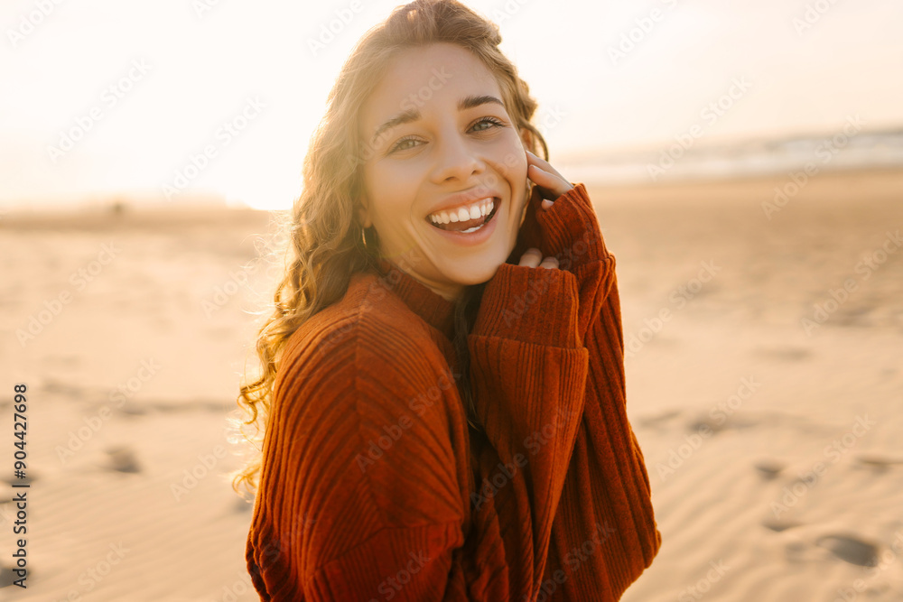 Portrait of a beautiful woman on the beach at sunset. The girl walks along the beach and enjoys the warm autumn weather. Travel, weekend, relax and lifestyle concept. Portrait of a beautiful woman on the beach at sunset. The girl walks along the beach and enjoys the warm autumn weather. Travel, weekend, relax and lifestyle concept.