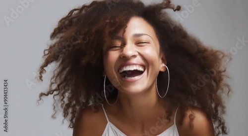 A happy black female laughing on a neutral background evoking a sense of playfulness