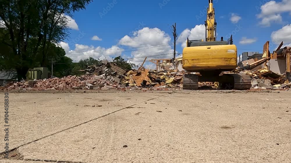 Rear view of an excavator demolishing a large brick building. The industrial claw works at dismantling and crushing the built structure into a pile of debris. Slow motion. Rear view of an excavator demolishing a large brick building. The industrial claw works at dismantling and crushing the built structure into a pile of debris. Slow motion.