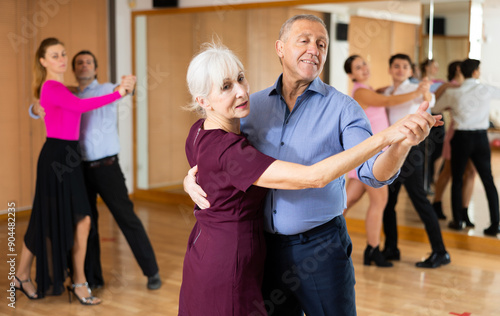 among small group of students at dance lesson, older positive partners dance waltz photo