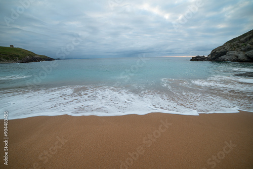 Tranquil scene of Tagle Beach in Cantabria, Spain, showcasing rugged rocks, gentle waves, and an expansive horizon. Perfect for travel, nature, and coastal themes. photo