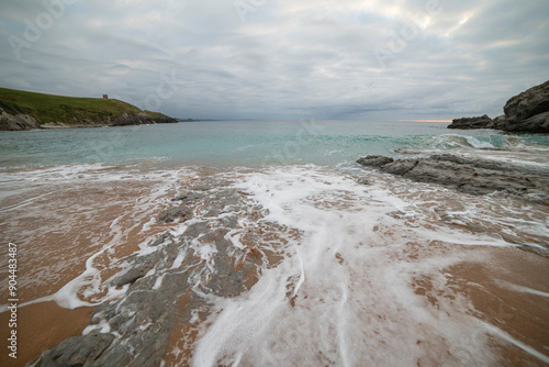 Tranquil scene of Tagle Beach in Cantabria, Spain, showcasing rugged rocks, gentle waves, and an expansive horizon. Perfect for travel, nature, and coastal themes. photo