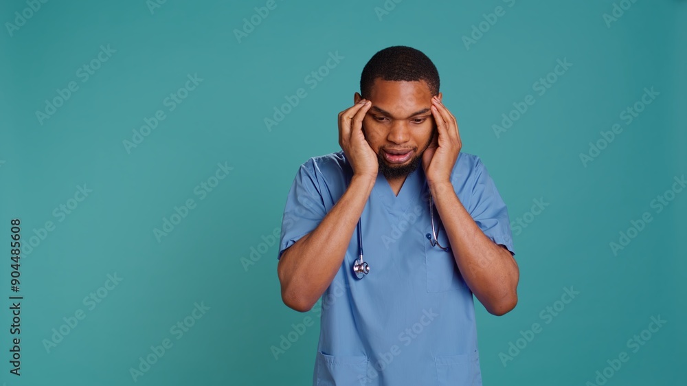 Fatigued nurse suffering from migraine pain after tiresome day at work. Hospital worker isolated over studio background affected by distressing headache during demanding job shift, camera B Fatigued nurse suffering from migraine pain after tiresome day at work. Hospital worker isolated over studio background affected by distressing headache during demanding job shift, camera B