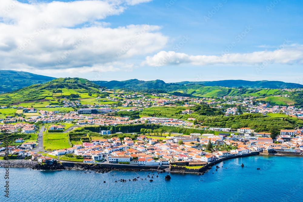 View of Horta town on ocean coast with green farming hills in background, Faial island, Azores, Portugal View of Horta town on ocean coast with green farming hills in background, Faial island, Azores, Portugal