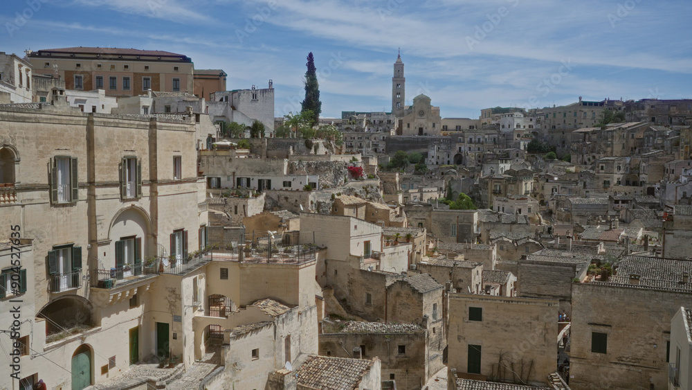 Fototapeta premium Historic rooftops and stone buildings under a bright sky in matera, basilicata, italy, showcasing ancient architecture and scenic views.