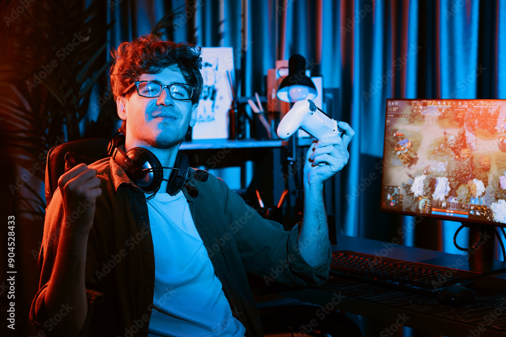 Fototapeta premium Host channel of young gaming streamer looking at camera, holding joystick with fighting Moba battle arena game with multiplays team against on pc screen background at neon digital light room. Gusher.
