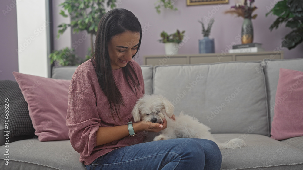 A smiling young woman enjoying time with her fluffy white maltese dog in a cozy living room setting. A smiling young woman enjoying time with her fluffy white maltese dog in a cozy living room setting.
