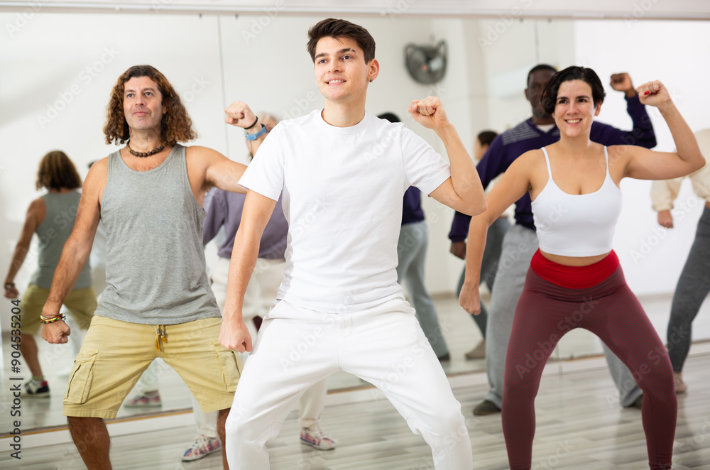 Fototapeta premium Group of active people practice sport dancing by taking part in a dance studio