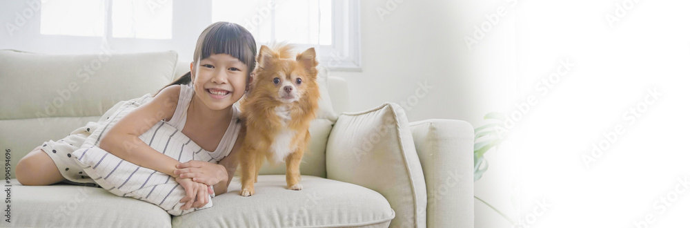 Portrait of little asian girl stay home sit on the sofa living room with lovely dog. Happy moment of pure love toddler playing with little dog, minimal happy pet animal lifesty banner Portrait of little asian girl stay home sit on the sofa living room with lovely dog. Happy moment of pure love toddler playing with little dog, minimal happy pet animal lifesty banner