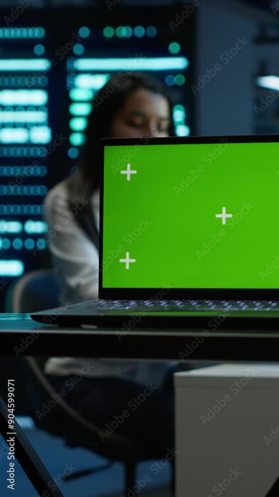 Vertical video Focus on mockup laptop used by technician in data center in blurry background managing servers. Close up of chroma key notebook used by expert in server hub to ensure networks are Vertical video Focus on mockup laptop used by technician in data center in blurry background managing servers. Close up of chroma key notebook used by expert in server hub to ensure networks are