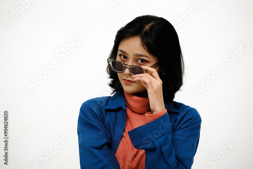 Fashion Indonesian or Asian woman touching sunglasses and looking at camera, isolated on white background